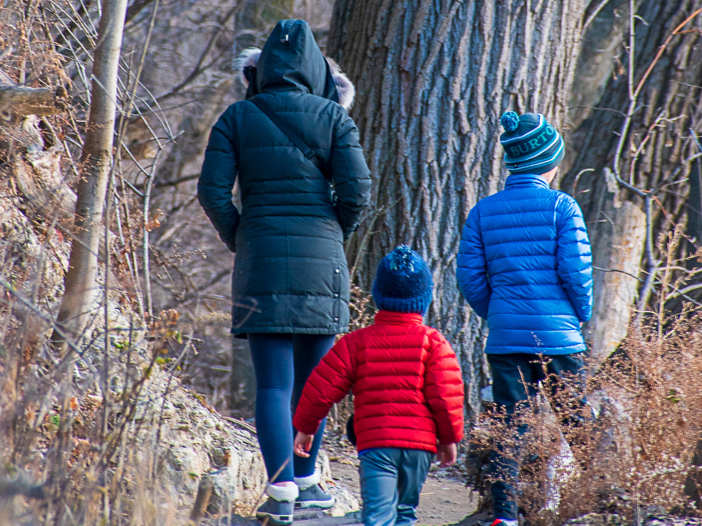 A woman and two boys walk along the Milwaukee River at Estabrook Park